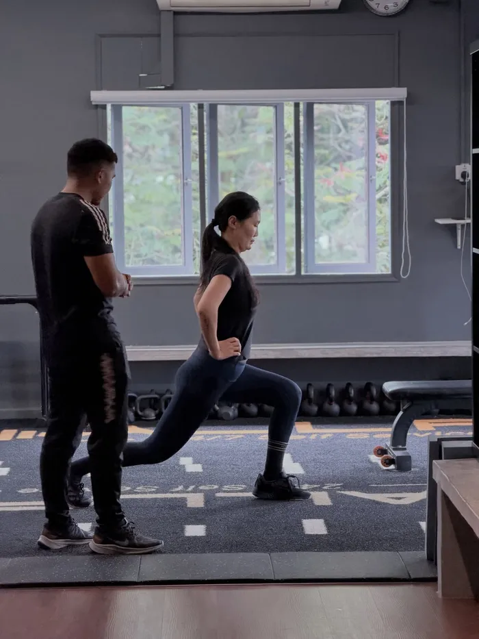 A Moov coach helping a woman practise a lunge